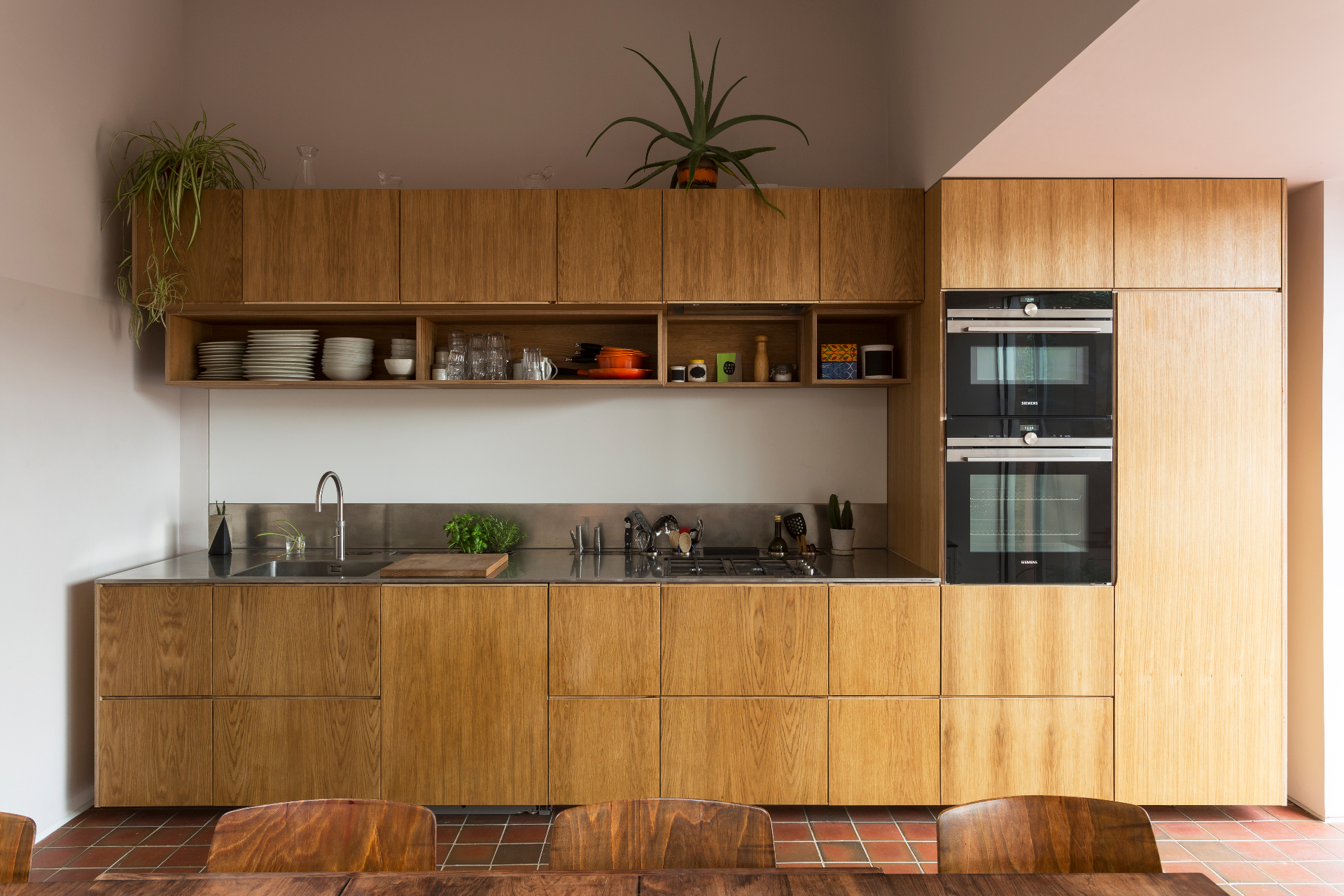 Oak kitchen cabinetry with continuous grain, open shelving and integrated ovens